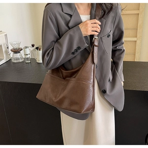 Detail of dark brown faux leather tote bag showing wax texture on a model shoulder