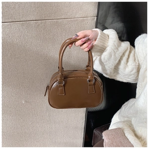 Dettaglio borsa bowling vintage marrone con texture in pelle liscia e manici robusti