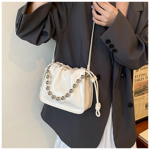 Detail of white glossy drawstring bucket bag with silver bead chain and shoulder strap