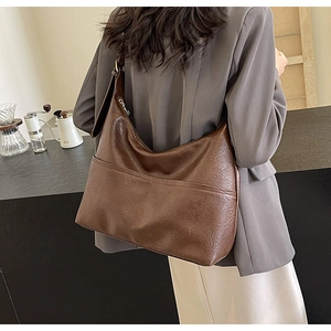 Detail of a large brown hobo bag with adjustable strap and textured synthetic leather