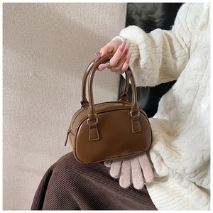 Dettaglio di una mini borsa Boston marrone con finitura lucida e cerniera in metallo argento