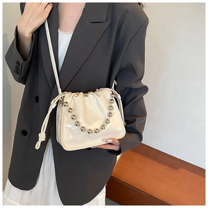 Detail of cream patent leather drawstring bag with silver bead chain and metal logo