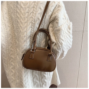 Borsa bowling vintage marrone abbinata a un maglione bianco a trecce per l'autunno