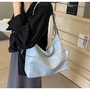 Detail of light blue hobo bag with soft texture and front pocket on a casual model