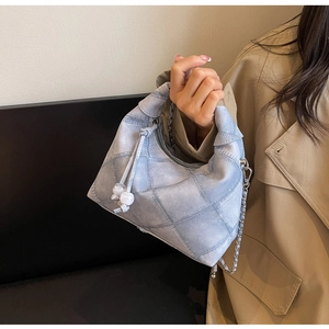 Detail einer hellblauen gesteppten Jeanshandtasche mit Kordelzugperlen und Kette