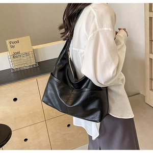 Detail view of large black faux leather hobo bag with side pockets and golden zipper