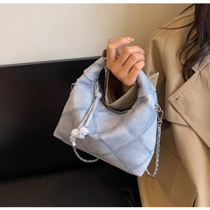 Detail der hellblauen Denim-Tasche mit Steppnähten und silbernem Kettenriemen