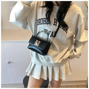 Détail d'un mini sac en cuir noir brillant avec boucle pyramide argentée et anse perles