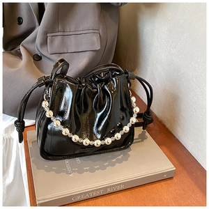 Detail of black glossy drawstring bucket bag with decorative silver beaded handle