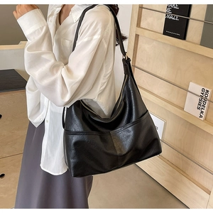 Detailed side view of black leather hobo bag with wide strap and metallic zipper closure