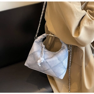Nahaufnahme hellblaue gesteppte Jeans-Handtasche mit Knotengriff und feiner Metallkette