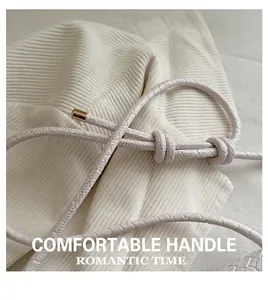 Detail of white knitted crossbody bag with leather woven strap and gold metal buckles