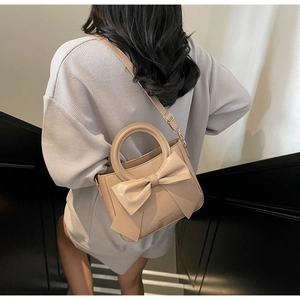 Fashionable beige bucket bag featuring a large bow detail and elegant round handles