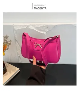 Close-up of fuchsia crescent underarm bag with gold bow detail and zipper closure