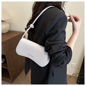 Detail of white woven texture shoulder bag with knot strap and gold logo lettering
