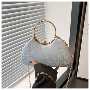 Macro shot of light blue evening bag with floral embroidery and golden metal ring handle