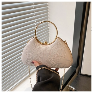 Detail of beige embroidered evening bag with 3D floral patterns and gold metal handle