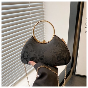 Detail of black floral jacquard evening bag with golden ring handle and chain strap