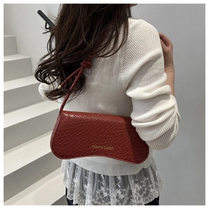 Détail du sac à bandoulière bordeaux motif crocodile avec bandoulière nouée élégante