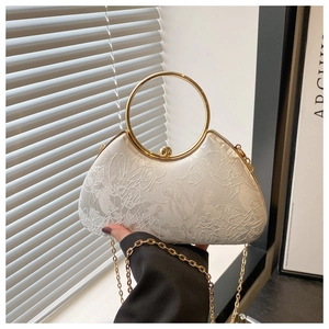 Detail of white lace evening bag featuring 3D floral embroidery and round gold handle