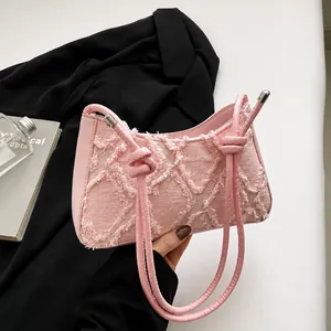 Detail of pink quilted tote bag showing fringe edges and knotted strap with silver hardware