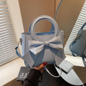 Elegant light blue bucket bag with a large bow detail and thin shoulder strap