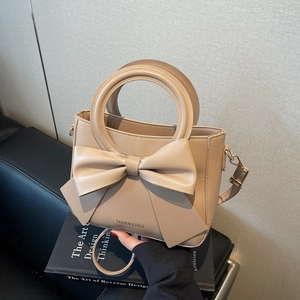 Chic beige bucket bag with large bow detail and round handle for women