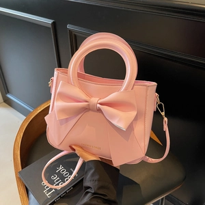 Pink bucket bag with large bow and golden text shown from a front perspective