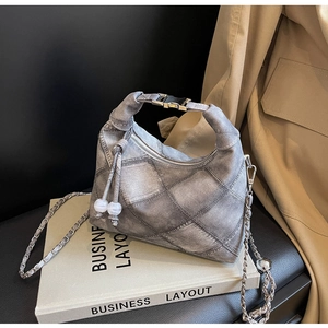 Details der grauen Denim-Tasche mit Steppmuster, Metallkette und Perlenanhängern