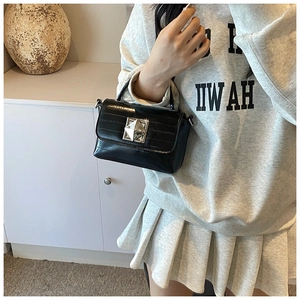 Détail d'un sac en cuir noir brillant avec boucle carrée en cristal et poignée courte