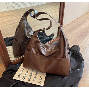Detail of dark brown faux leather tote bag with dual front pockets and adjustable strap
