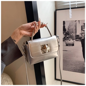 Détail du petit sac carré argenté avec boucle géométrique et poignée en chaîne de perles