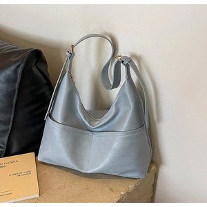 Detail of light blue PU leather tote bag with front pockets and adjustable strap