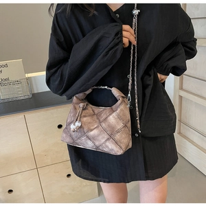 Detail der braunen Vintage-Tasche mit silbernem Metallgriff und Kettenriemen