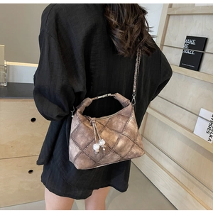 Detail der braunen Stepptasche mit Anhänger, kombiniert mit einem schwarzen Outfit