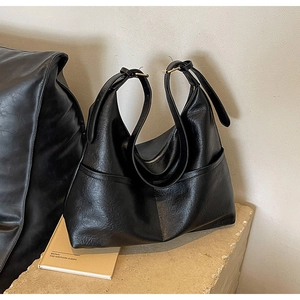 Detail of black faux leather tote bag with grainy texture and side pocket for daily commute