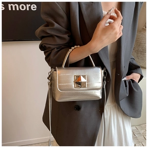 Détail du petit sac argenté effet miroir avec boucle géométrique sur un blazer gris