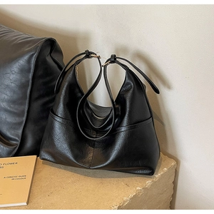 Detail shot of black faux leather tote showing soft lychee texture and metallic zipper