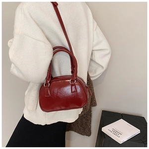 Dettaglio della borsa bowling rosso scuro con finitura lucida e accessori in metallo