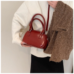 Elegante borsa a mano bordeaux portata a tracolla dalla modella con un outfit chic