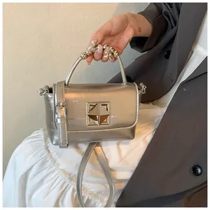 Détail du sac argenté métallisé avec poignée perlée et boucle métallique carrée