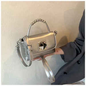 Détail du sac argenté texturé avec poignée en perles métalliques et boucle géométrique chic