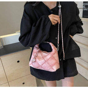 Detail der rosa gesteppten Beuteltasche mit Metallkette und Kugelverzierung am Model