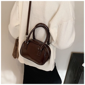 Borsa Boston in pelle lucida marrone scuro abbinata a un maglione di maglia color crema