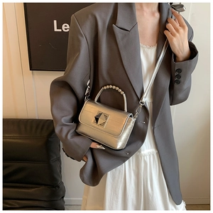 Détail du sac argenté métallisé avec texture crocodile et fermoir à clous carrés