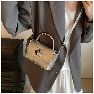Détail du sac en cuir métallisé argenté avec poignée perlée et fermoir en métal