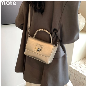 Détail du sac bandoulière doré champagne avec poignée perle et fermoir carré
