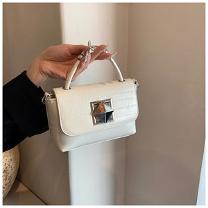 Détail du sac crème à motif crocodile avec une poignée ornée de perles argentées