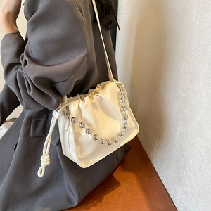 Chic cream white drawstring bucket bag with silver bead chain shown on a model