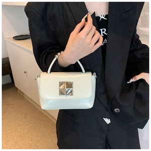 Détail d'un sac à main crème avec poignée à boules métalliques et boucle argentée